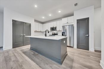 A modern kitchen with a grey island and stainless steel appliances at Luxe 360 on Centerpointe Apartments, Midlothian, 23114